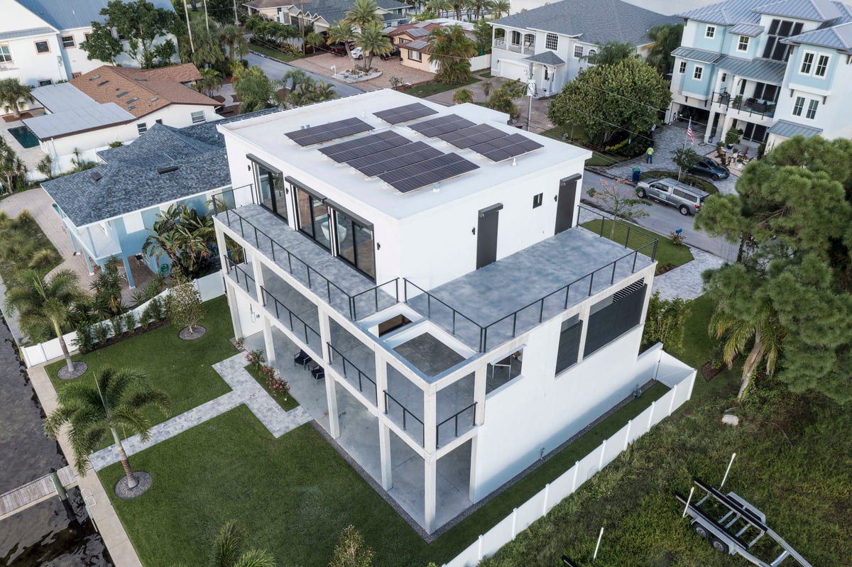 Image of aerial view of modern white three story home with solar array on roof