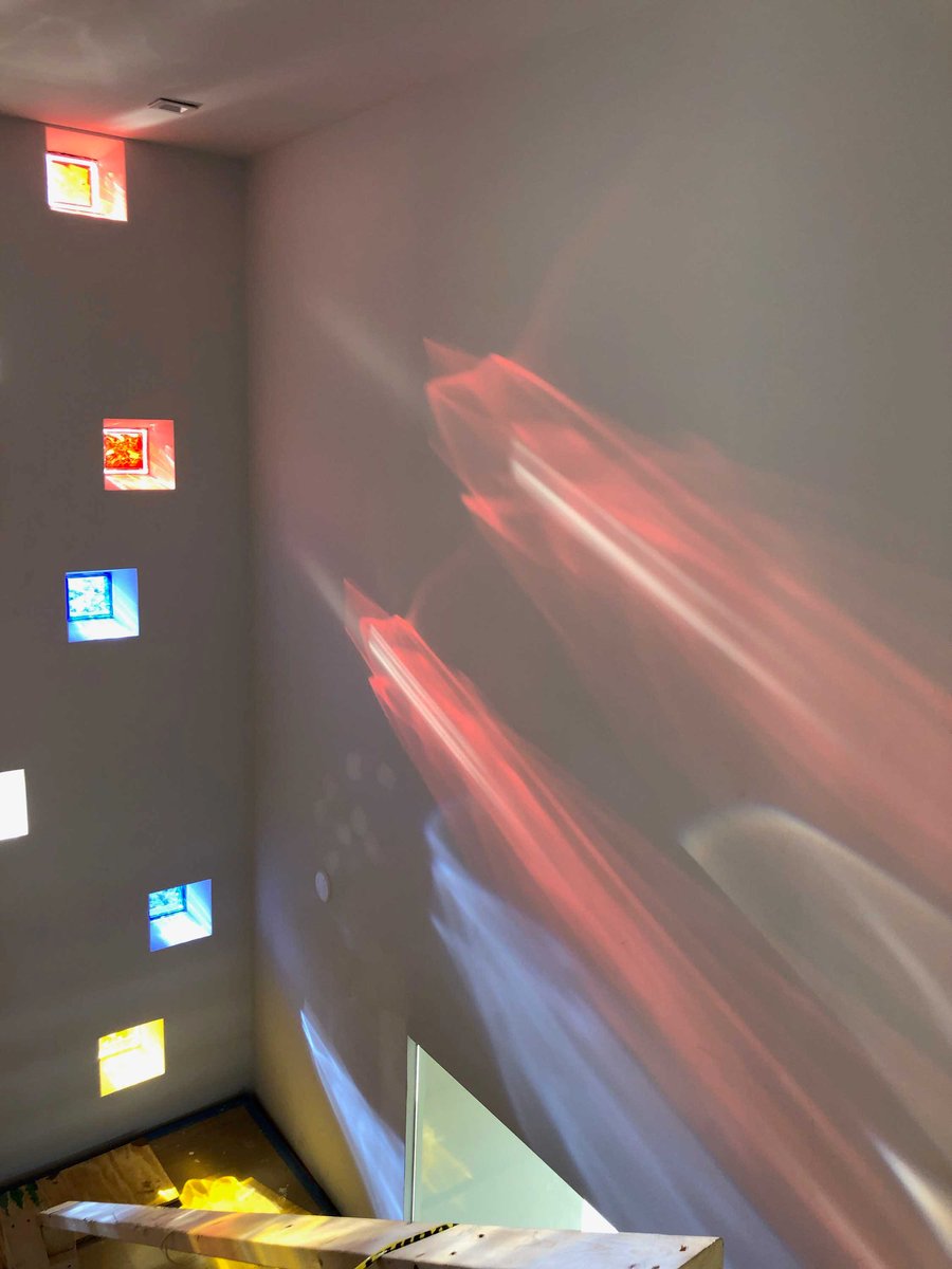 Image of tall stairway with colored light cascading in from custom colored glass blocks inset in exterior wall