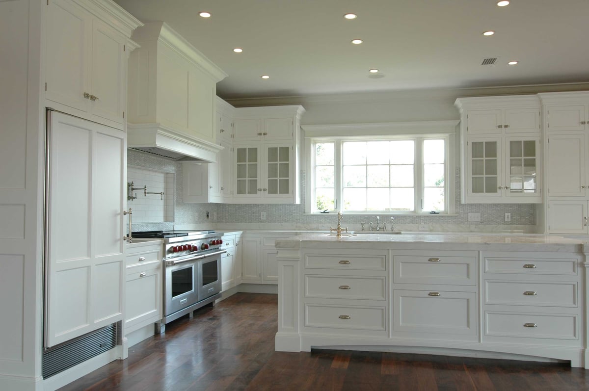 Image of kitchen with dark wood floors, traditional style cabinetry, and large kitchen island