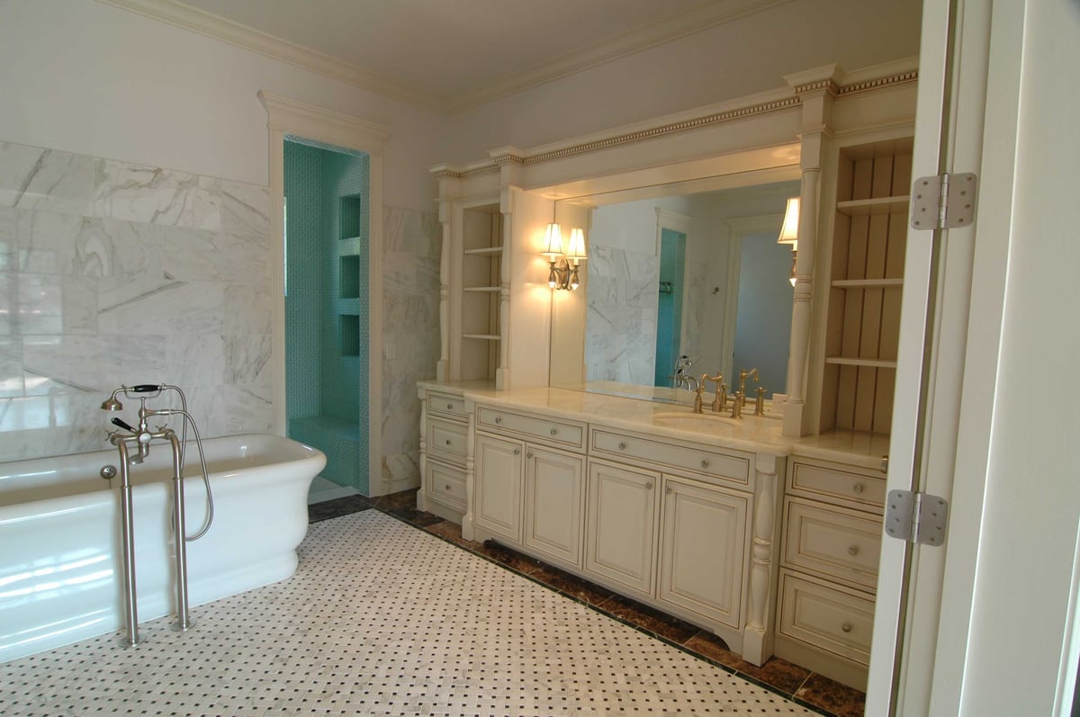 Image of large bathroom with curved wall bathtub, large furniture styled vanity and storage, and detailed tile floor pattern